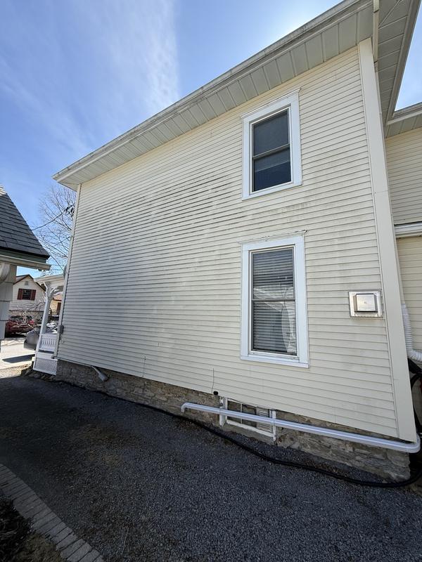 Before: Cream vinyl siding with dark streaks across the wall