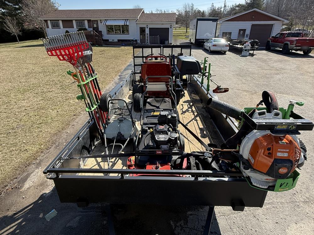 Our trailer loaded for the mowing route with a stand-on mower, a walk-behind mower, trimmers and a backpack blower